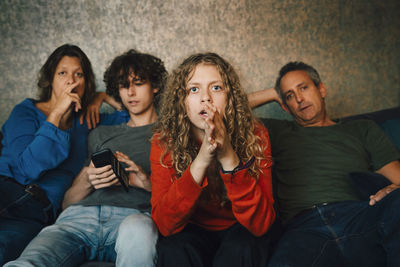 Group of people looking away while sitting on sofa