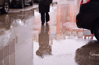 Low section of man standing on wet street in rainy season