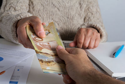 People holding paper currency at table in office