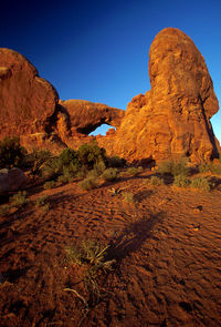 Rock formations on landscape against clear blue sky