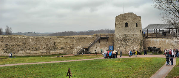 People in front of historic building against sky