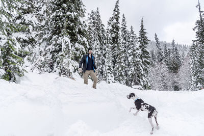 Portrait of man and dog on snow covered field