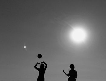 Silhouette people playing with ball against sky