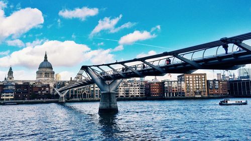 Low angle view of millennium bridge over river leading towards st pauls cathedral against sky