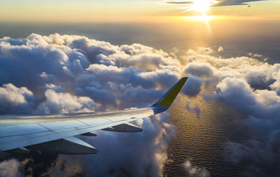Aerial view of aircraft wing against sky during sunset