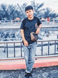 Young man looking away while standing on railing