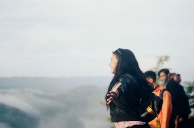 Side view of woman looking at sea against sky