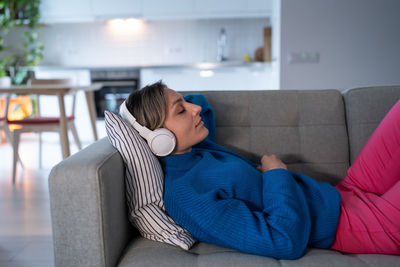 Side view of young woman sitting on sofa at home