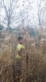 Boy in forest against sky