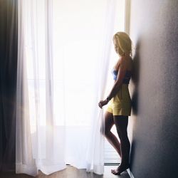 Young woman standing against window