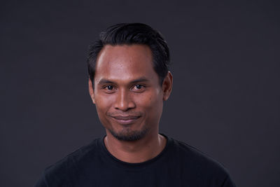 Portrait of a smiling young man against black background