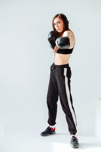 Portrait of young woman standing against white background