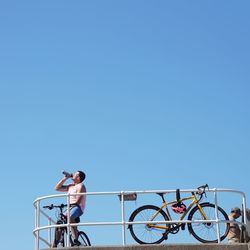 People riding bicycle against clear blue sky