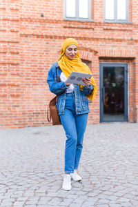 Full length of woman standing against wall