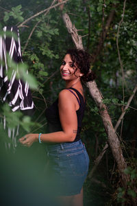 Woman standing by tree in forest