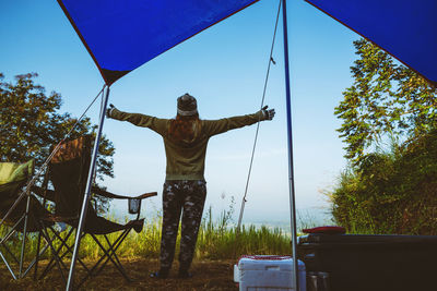 Rear view of woman standing by tent against sky