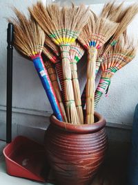 Brooms in container against wall