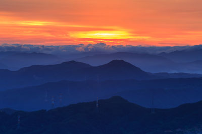 Scenic view of silhouette mountains against orange sky