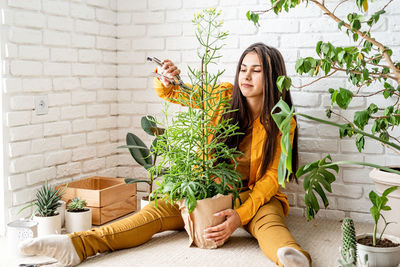 Young woman standing by potted plants