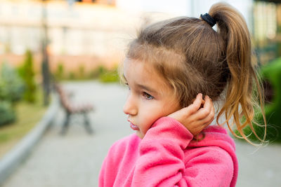 A little girl with a sad and frightened face holds her cheek with her hand - a tooth hurts. 