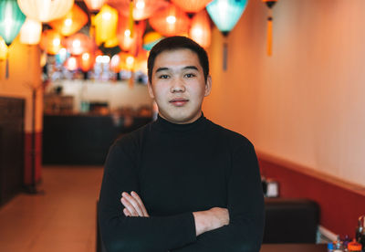 Handsome young asian man in black clothes in festive chinese vietnamese restaurant 