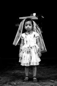 Full length of cute girl standing against wall at night