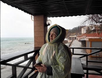 Portrait of an elderly woman pensively looking at the sea in inclement rainy weather.