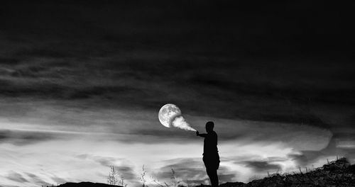 Low angle view of silhouette man standing against sky at night