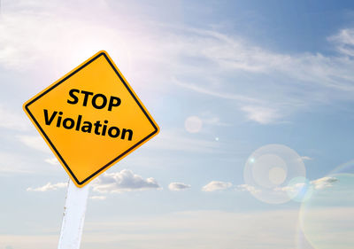 Close-up of road sign against sky