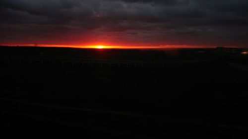 Silhouette landscape against dramatic sky during sunset