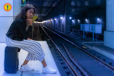 Woman sitting on railroad station platform