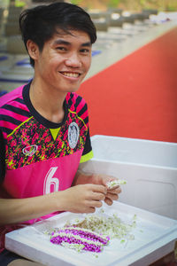 Portrait of smiling man making floral garland