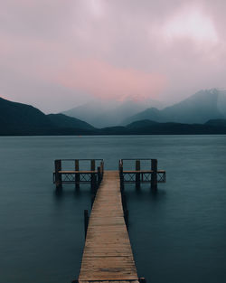 Pier over lake against sky during sunset