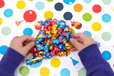 Low section of child holding multi colored pencils on table