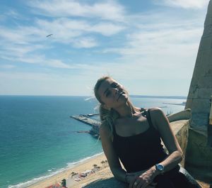 Young woman standing by sea against sky