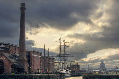 Sailboats in city against cloudy sky