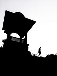 Low angle view of silhouette man walking against clear sky