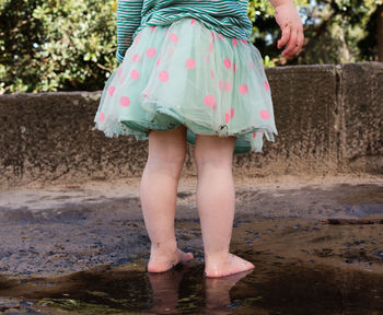 Low section of girl standing in puddle