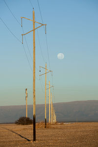 Electricity pylon on field against clear sky