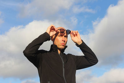 Low angle view of young man photographing against sky