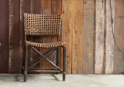 Empty chairs and table against window of old building