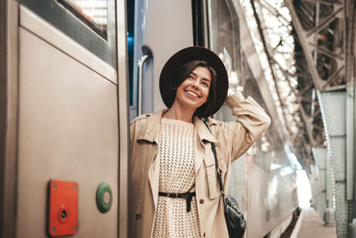Young stylish woman traveler hanging and smiling on the train