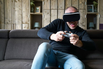 Full length of man using mobile phone while sitting on sofa