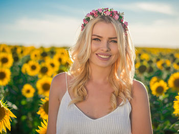 Portrait of smiling woman wearing wreath against sunflower field