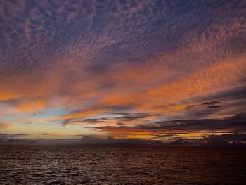 Scenic view of sea against dramatic sky during sunset