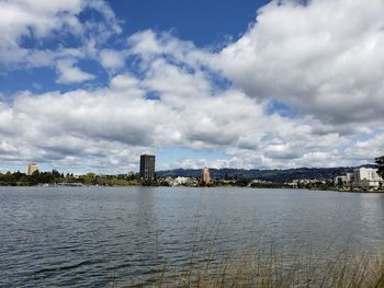 View of buildings by river against cloudy sky