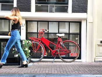 Woman with bicycle on sidewalk by building in city