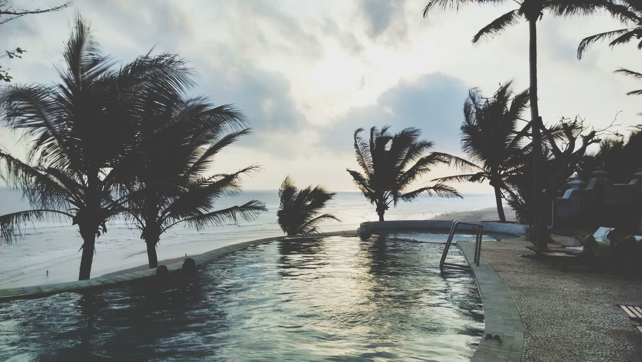 water, tree, sky, cloud - sky, tranquility, tranquil scene, palm tree, sea, scenics, nature, cloud, beauty in nature, silhouette, cloudy, waterfront, lake, idyllic, outdoors, day, reflection