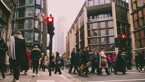 People walking on street amidst buildings in city