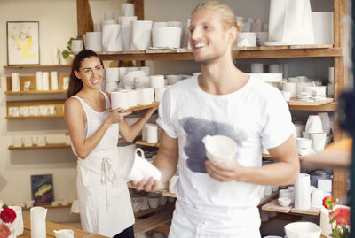 Happy workers arranging craft products at crockery workshop